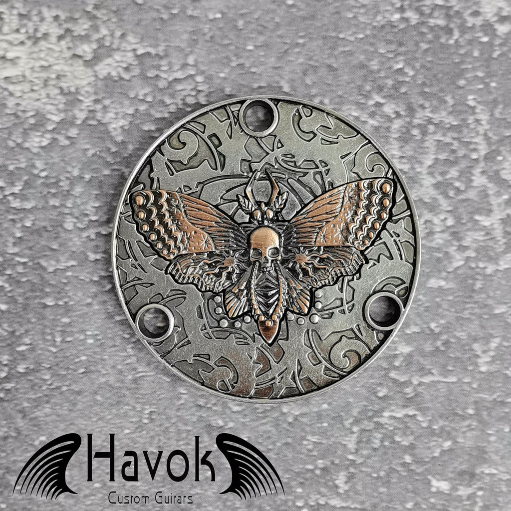 A vintage style metal neck plate for electric guitars with skull moth design. The diameter is 54mm and the thickness is 3mm.