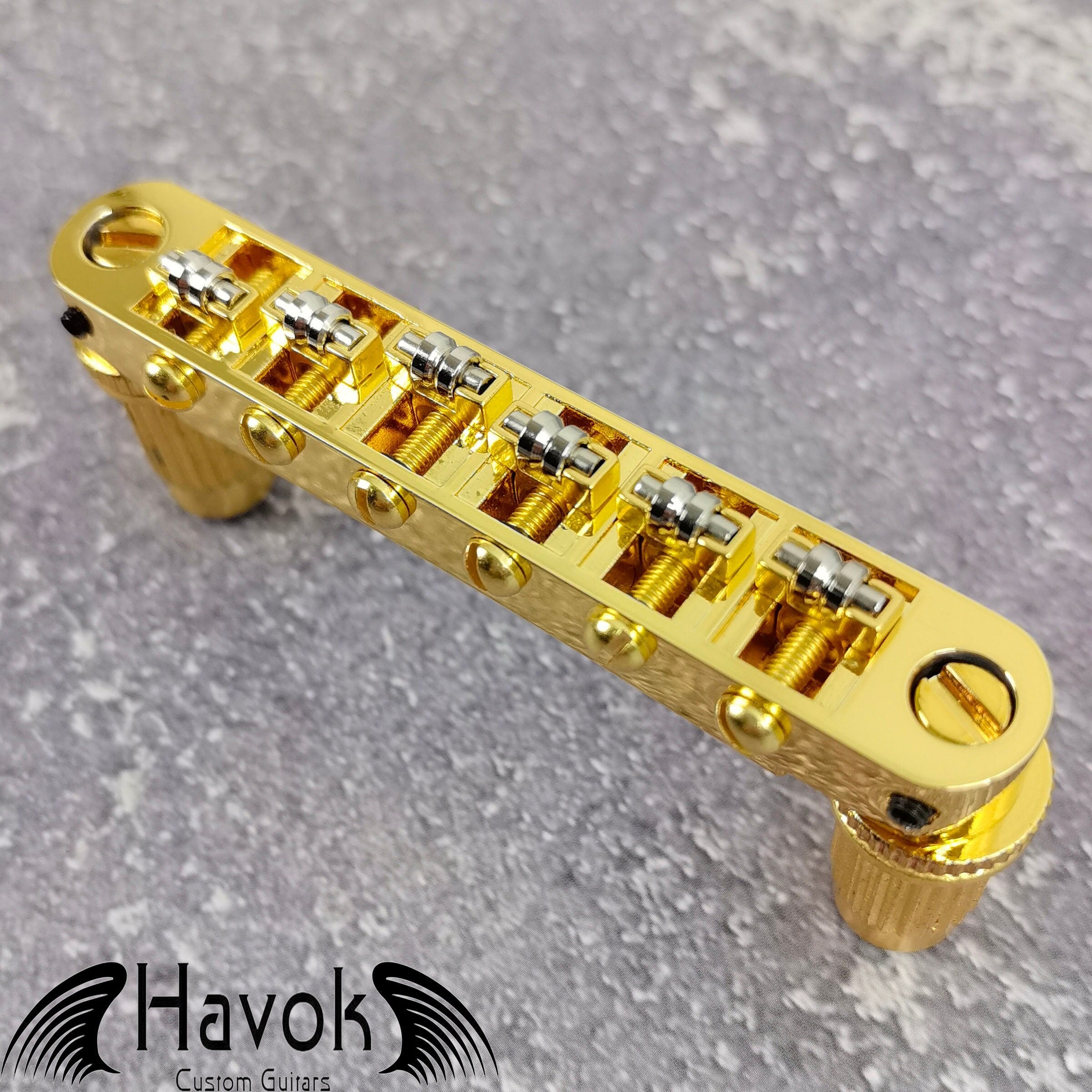 A gold tune-o-matic bridge for 6 string electric guitars like Gibson. It is has high quality and perfect for guitar building.
